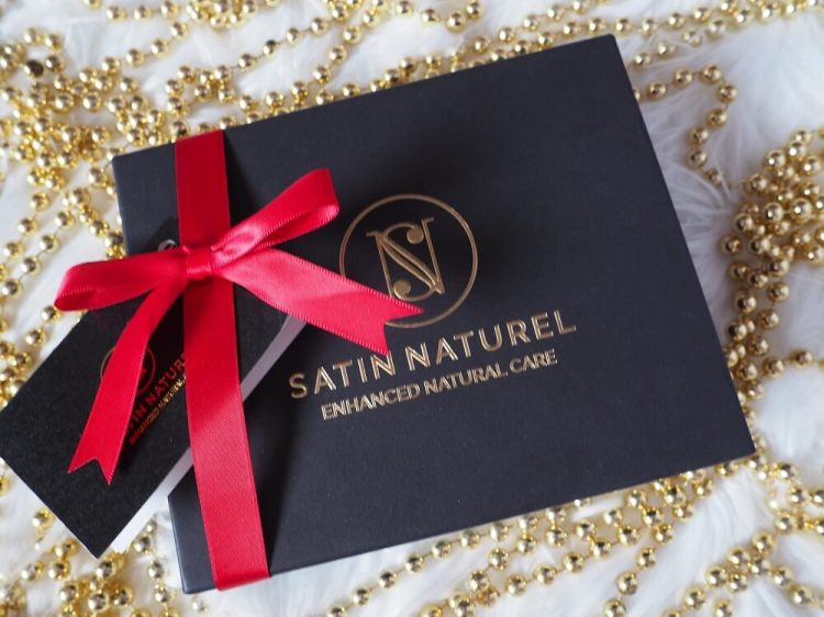 Schwarze Geschenkbox mit goldener Prägung, roter Schleife und kleinem Kärtchen – luxuriöse Satin Naturel Badepralinen verpackt für ein Spa-Erlebnis zu Hause.