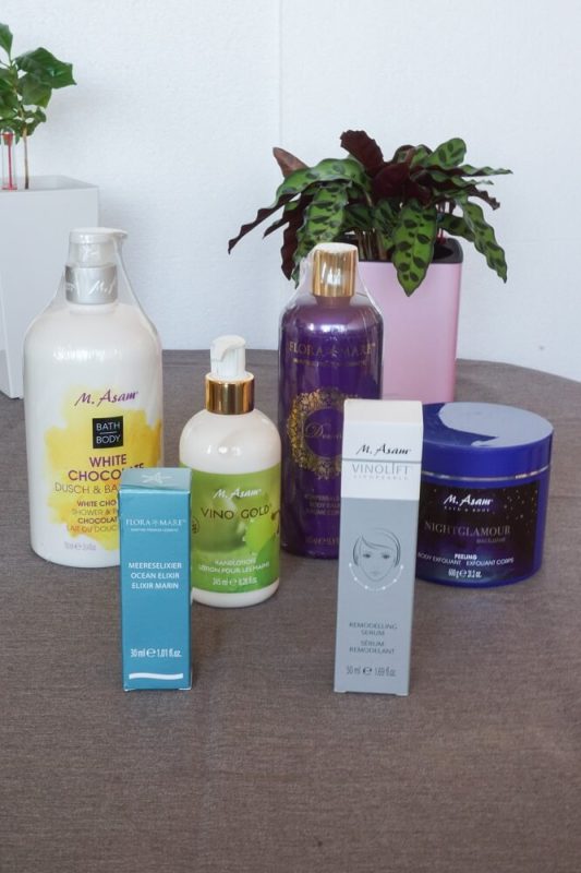 Hochkantaufnahme der Asam Beauty Produkte aus einer Geschenktüte – Pflegeprodukte ausgepackt und arrangiert für den Produkttest.