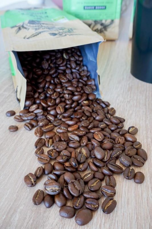 Geöffnete Packung Tchibo Bio Kaffee, daneben gestreute Kaffeebohnen in Nahaufnahme – aromatischer, nachhaltiger Genuss im Detail.