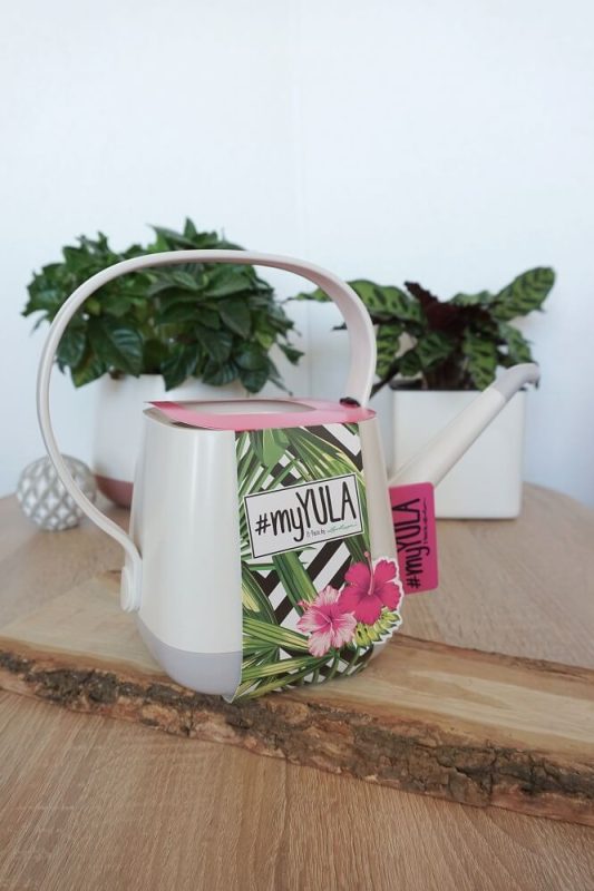 Weiße Lechuza #myYula Gießkanne auf Holzbrett, hochkant, mit Lechuza-Pflanztopf im Hintergrund – stilvolles Gießzubehör für Pflanzenfreunde