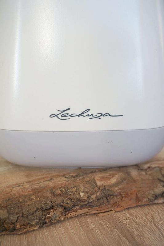 Nahaufnahme der weißen Lechuza #myYula Gießkanne auf Holzbrett mit sichtbarem Logo – stylisches Gießzubehör für Pflanzenfreunde