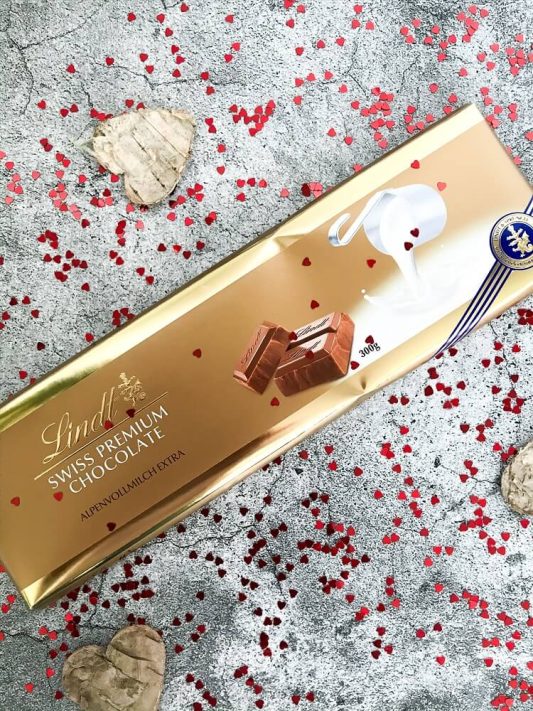 Lindt Riesen-Tafel „Alpenvollmilch Extra“ in goldener Verpackung – große Vollmilchschokolade dekorativ präsentiert.