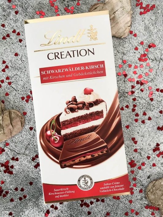 Lindt Creation „Schwarzwälder Kirsch“ – Vollmilchschokolade mit Kirschen und Gebäckstücken, cremige Füllung sichtbar.