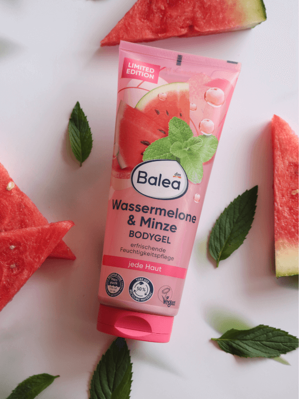 Tube des Balea Bodygels Wassermelone-Minze, umgeben von frischen Wassermelonenstücken und Minzeblättern